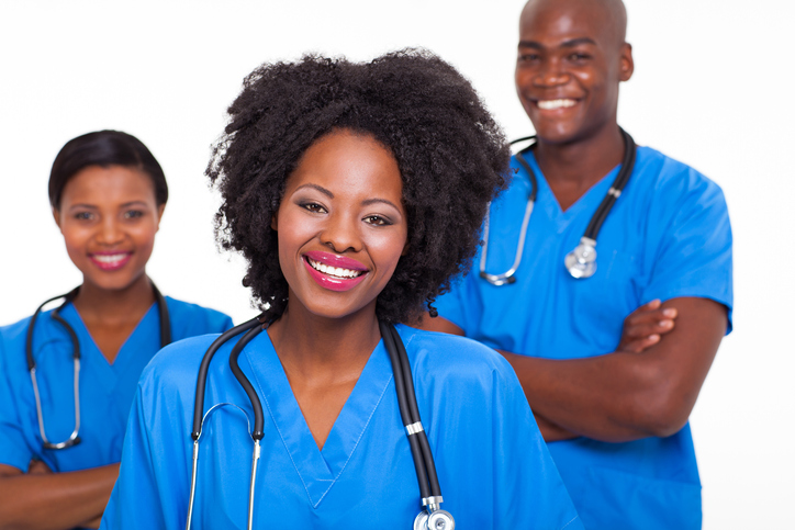 Three people in blue scrubs with stethoscopes standing together